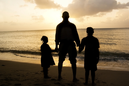 father and children silhouette at beach